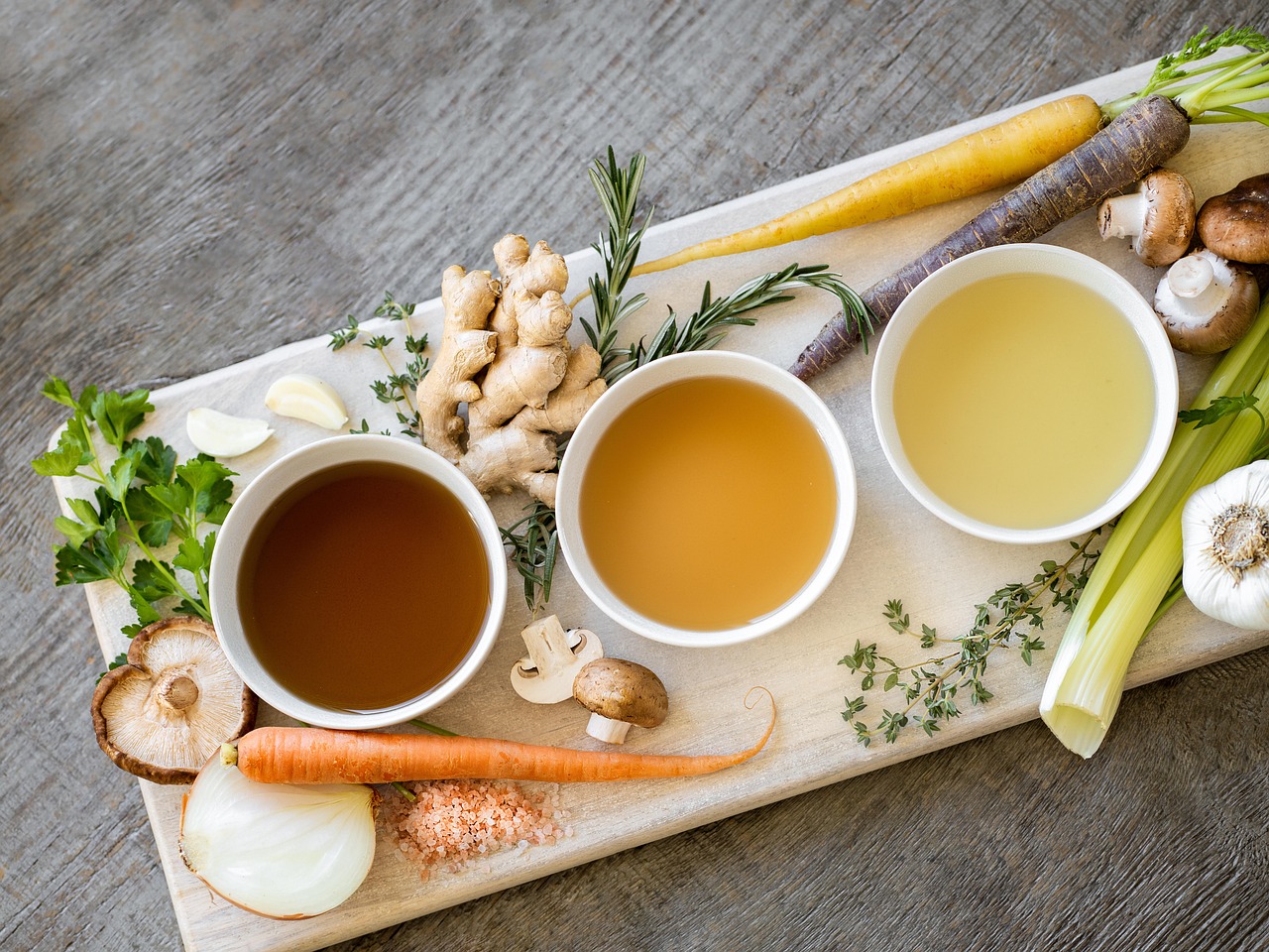 3 bowls with Broth/Soup and Vegetables on a chopping board