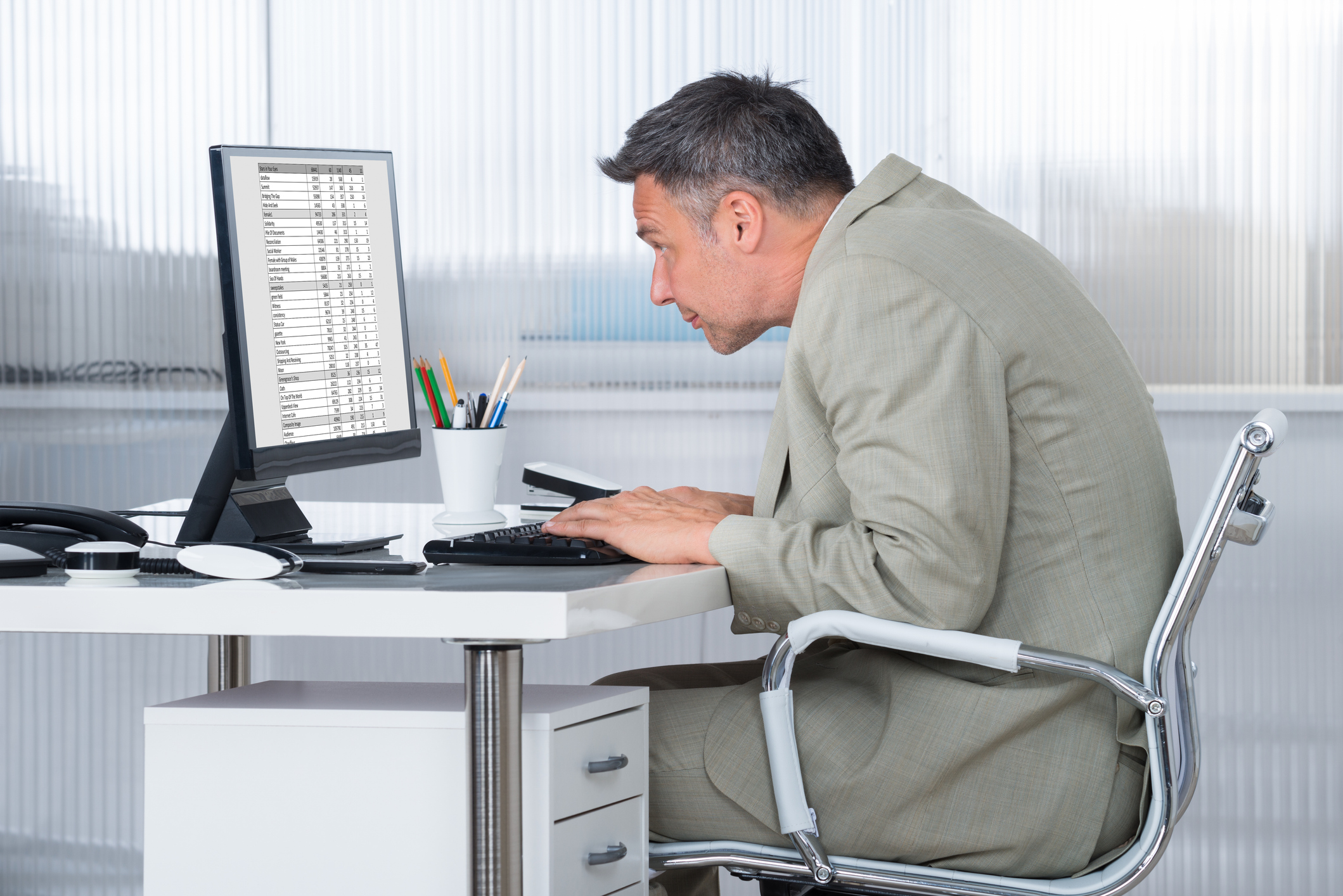 Man leaning forward at a computer with poor sitting posture