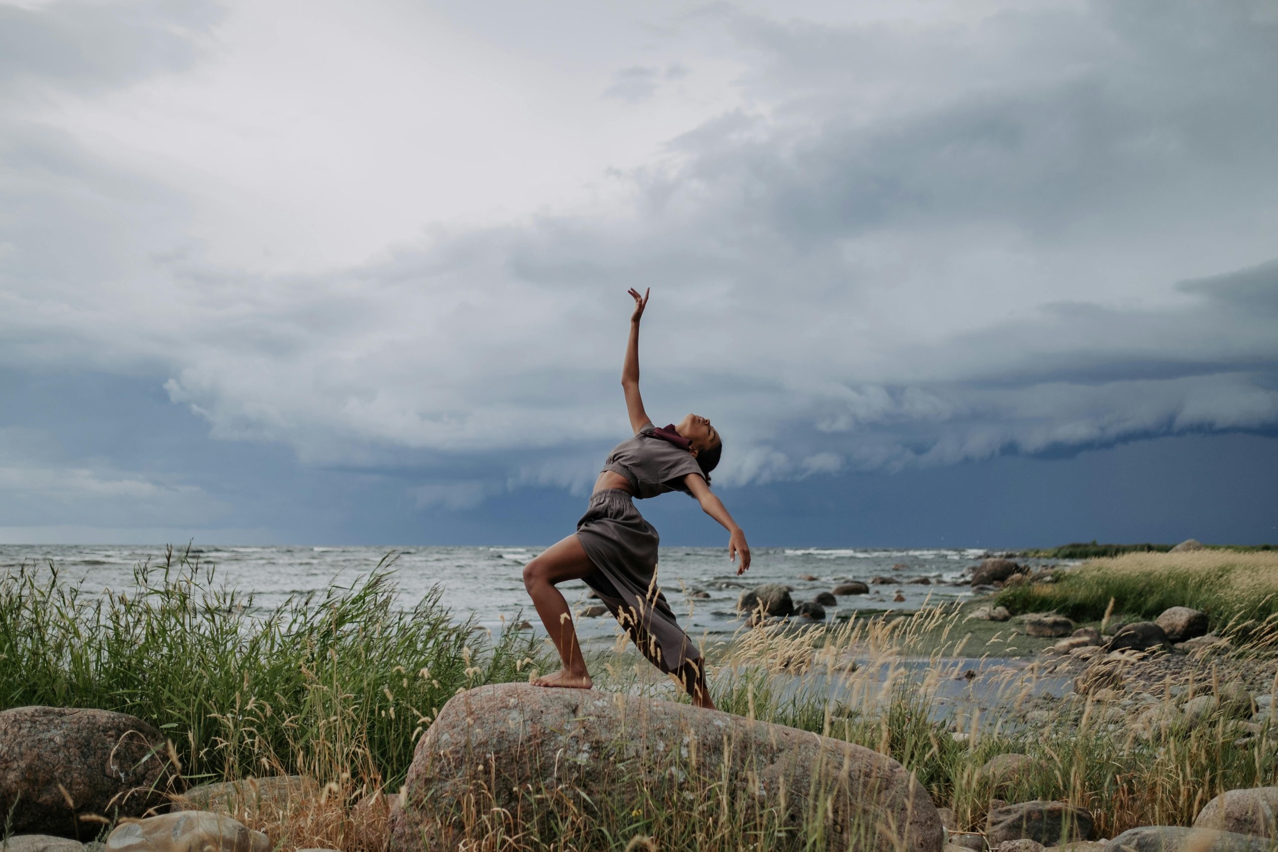 Woman in Gray Costume Dancing on Top of a Rock