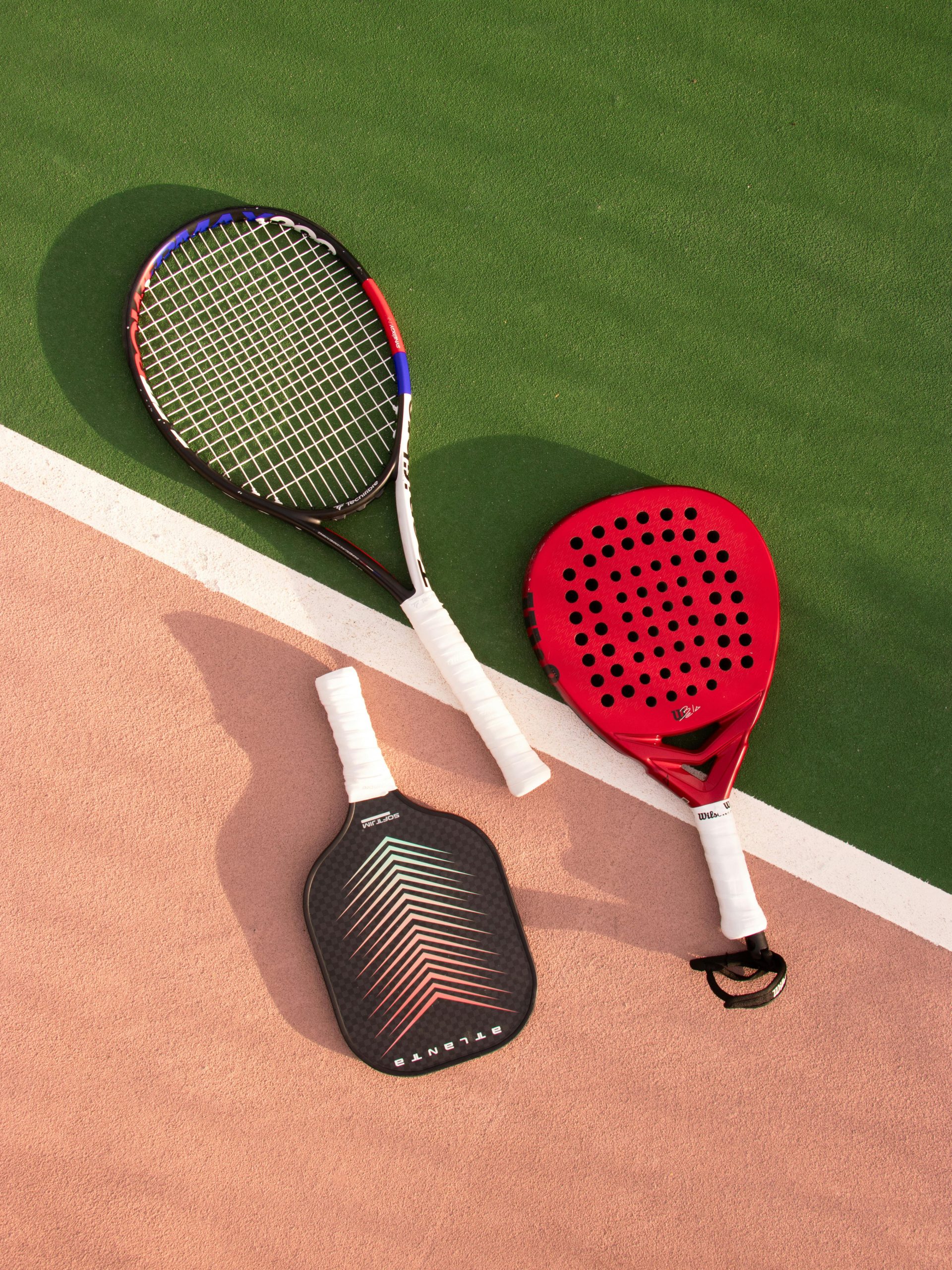 Tennis, pickleball, and padel rackets on a court